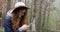 Girl in a hat with a telephone in a coniferous forest