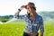 Girl with hat wearing shirt in a field with water sprinklers