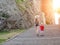 Girl in a hat with a young son walking near the walls of the fortress, sunlight. Back view