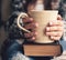 Girl having a break with cup of fresh coffee after reading books or studying