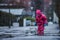 Girl is having fun in water on street in cold autumn day, girls splashing water in rain