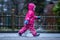 Girl is having fun in water on street in cold autumn day, girls splashing water in rain