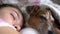 Girl head and dog muzzle lie together on pillow sleeping