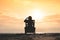 Girl in headphones is sitting on the sun lounger listening to music on the beach at sunset.