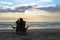 Girl in headphones is sitting on the sun lounger listening to music on the beach at sunset.