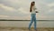 Girl in headphones walks in evening on beach with a tablet and listen to music.