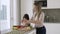 Girl helping her mom to cook salad for dinner