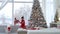 Girl helps her sister to get off the windowsill at the large panoramic window, behind which it is snowing.