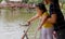 A girl and her mother feeding fish in a pond using food pellet