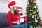 Girl and her mother wearing santa hat while opening christmas gift at home