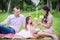 Girl with her parent sitting in park and watching flower