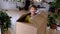 The girl hides in a big box and looks out of it funny in a room inside the home. Moving to a new house, unpacking things, renting