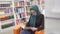 Girl in hijab reading book in library