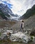 Girl in hike to the glacier, stands on a rock