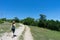 Girl hiker walking along a pathway with her backpack. Sport caucasian woman jogging in summer with hat and wood stick. Red head