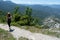 Girl hiker walking along a pathway with her backpack. Sport caucasian woman jogging in summer with hat and wood stick. Red head