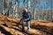 A girl in hiking clothes photographs landscapes in the mountains through an autumn beech forest