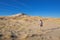 Girl hiking to sand dunes of Kelso in Mojave National Park with blue sky