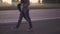 A girl hipster in ragged jeans and a sweatshirt with a hood walking along a deserted highway against a background of