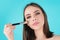 Girl hold blush blusher apply powder visage isolated over studio background. Young woman powdering cheeks. Makeup brush