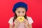 Girl hold glazed cute donut in hand red background. Kid playful girl ready to eat donut. Sweets shop and bakery concept