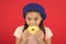 Girl hold glazed cute donut in hand red background. Kid playful girl ready to eat donut. Sweets shop and bakery concept