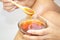 The girl is holding a bowl with a wooden spoon in her hands. With liquid sugar, for epilation. With liquid honey. Close-up.