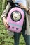 Girl holding cat packed in pink cat backpack with transparent window for a walk.