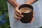 The girl holding a clay Cup of hot cappuccino closeup