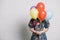 girl holding colorful balloons front her face standing against wall. High quality photo