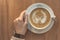 Girl holding a cup of fresh espresso cappuccino on a wooden table