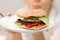 Girl holding delicious vegan burger on white plate in hand