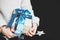 The girl is holding a gift with a blue bow in her hands. Gift in craft paper. Beautiful blue bow. A Christmas gift. New Year.
