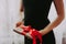 The girl is holding a gift with a red ribbon. A woman in a black dress on a white background is holding a box with red