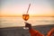 Girl Holding Glass of Drink on Beach at Beautyfull Romantic Sunset. Glass and Hand Close Up