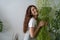 Girl holding green flower in her arms with joy in home garden. Take care and love house plants.