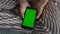 Girl holding green mobile in hands closeup. Teenager watch online blogs morning