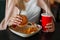 Girl holding a hamburger, eating fast food and drinking cola.