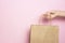 Girl holding in hand beige craft paper bag for shopping on pink background