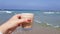 Girl holding in her hand latte coffee in transparent glass against sea waters