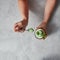 Girl holding ice cream in her hands with coconut shell and spoon with green dessert above a gray stone table.