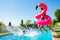 Girl holding inflatable rose flamingo jump in pool