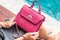 Girl holding luxury snakeskin python handbag on a swimming pool background. Tropical island Bali.