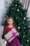 Girl holding magenta gift-box under christmas tree