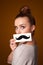 Girl holding paper with mustache drawing on gradient background