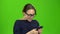 Girl holding a phone dials a message and paces . Green screen