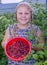 The girl is holding a ripe juicy red fragrant raspberry in her hands.