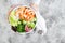 Girl holding shrimp poke bowl with seaweed, avocado, cucumber, radish, sesame seeds