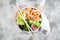 Girl holding shrimp poke bowl with seaweed, avocado, cucumber, radish, sesame seeds