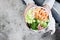 Girl holding shrimp poke bowl with seaweed, avocado, cucumber, radish, sesame seeds